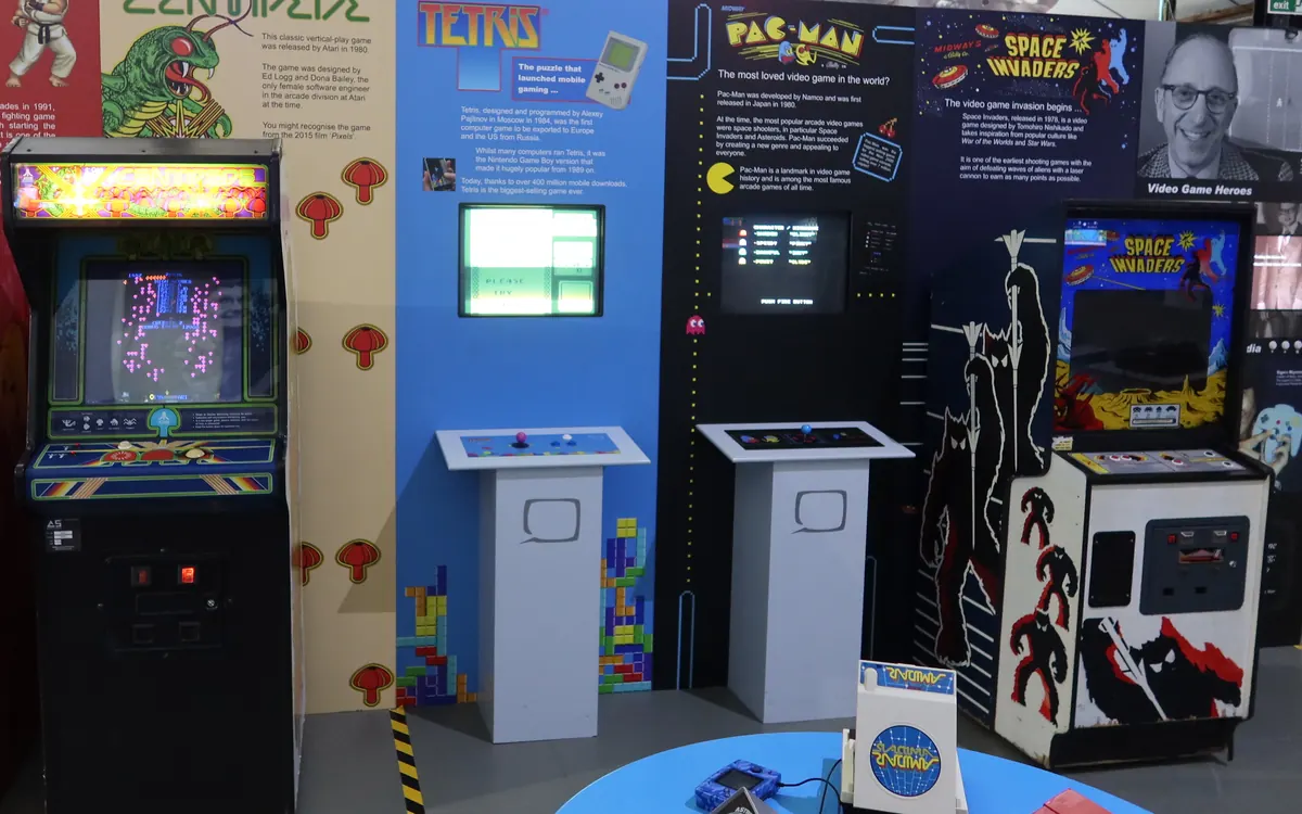 Classic arcade cabinets including Centipede and Space Invaders on display at a video game exhibition (illustrative photo)