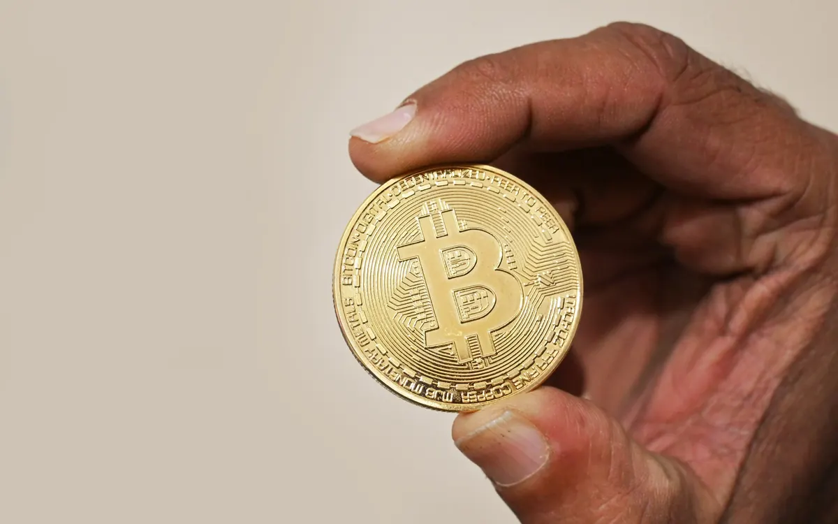 A hand holding a physical bitcoin coin (illustrative photo)