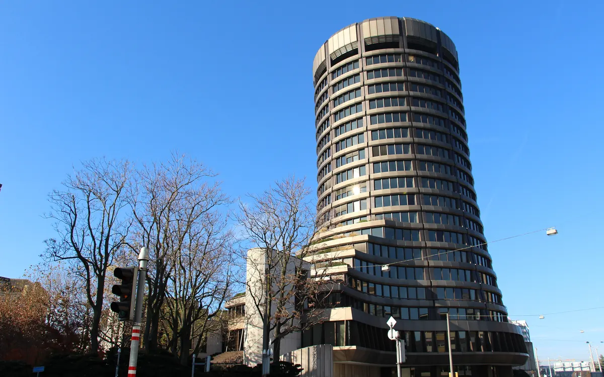 The round tower of the Bank for International Settlements in Basel under a blue sky