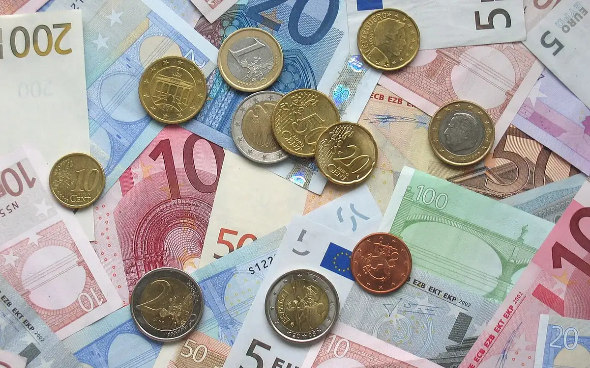 Euro banknotes and coins spread on a table (illustrative photo)