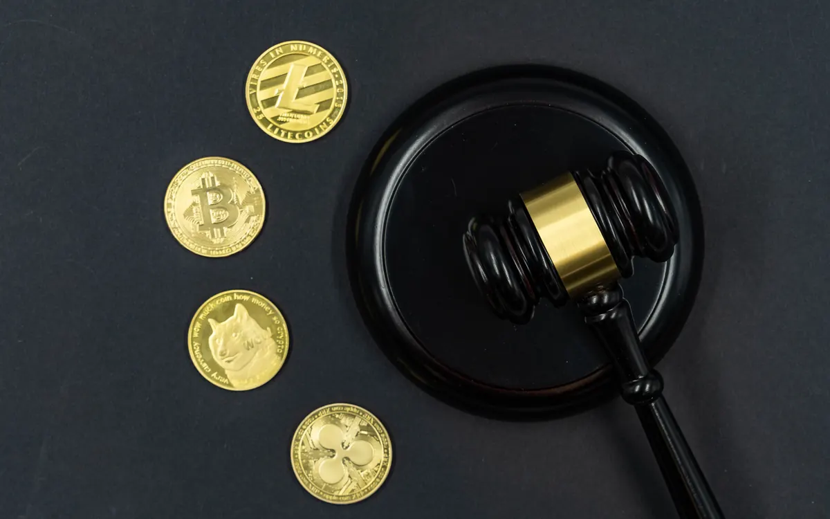 Physical crypto coins next to a judge's gavel (illustrative photo)