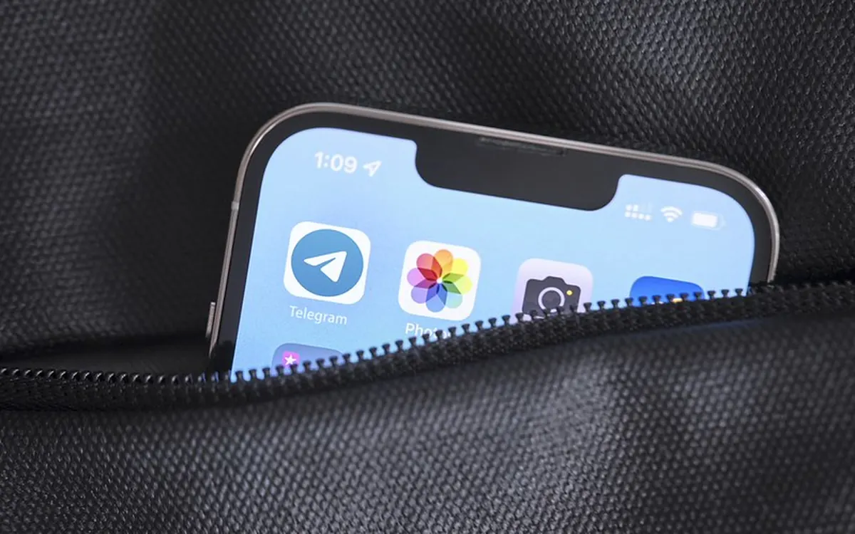 Smartphone with the Telegram app icon on its home screen, half tucked into a bag pocket (illustrative photo)