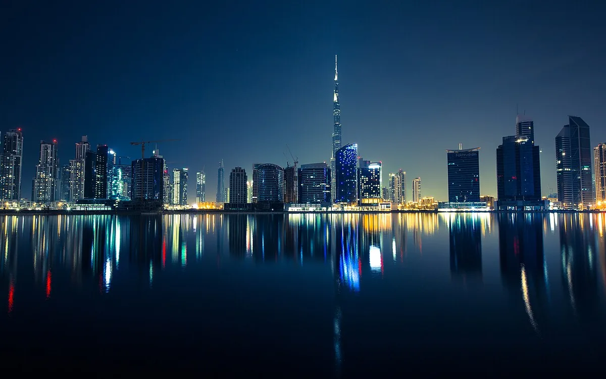 Downtown Dubai skyline with the Burj Khalifa reflected in the water at night (illustrative photo)