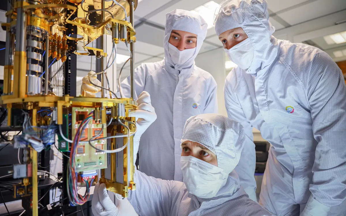 Researchers in cleanroom suits working on the wiring of a quantum computer cryostat (illustrative photo)