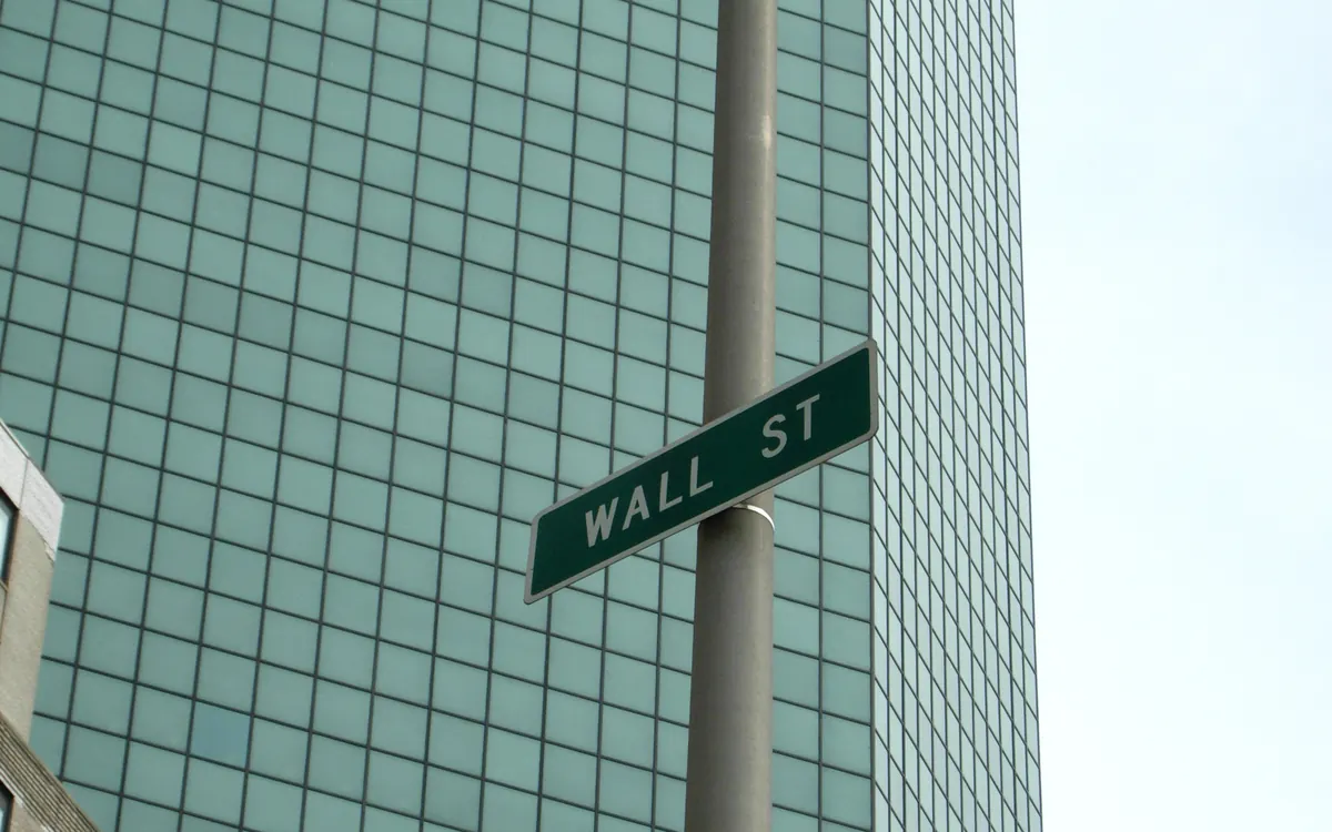 Wall St street sign in front of a glass office tower in New York (illustrative photo)