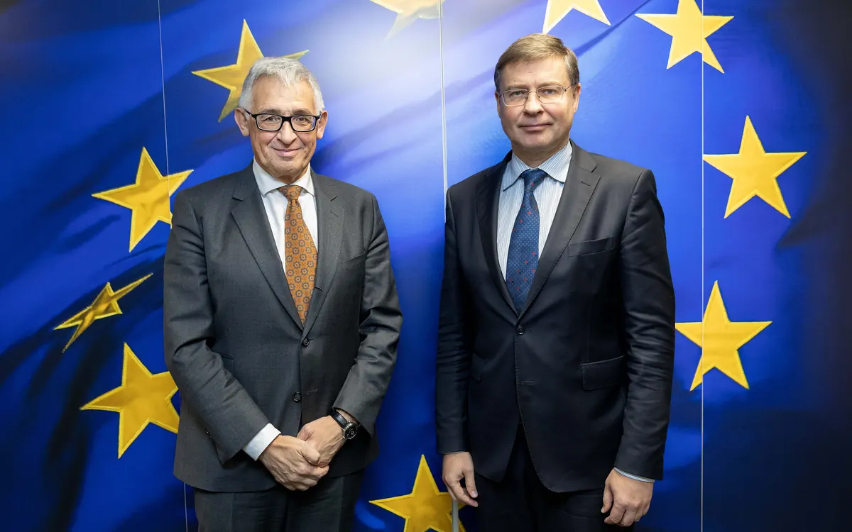 ECB Executive Board member Piero Cipollone, left, with EU Commissioner Valdis Dombrovskis in front of EU flags in 2024