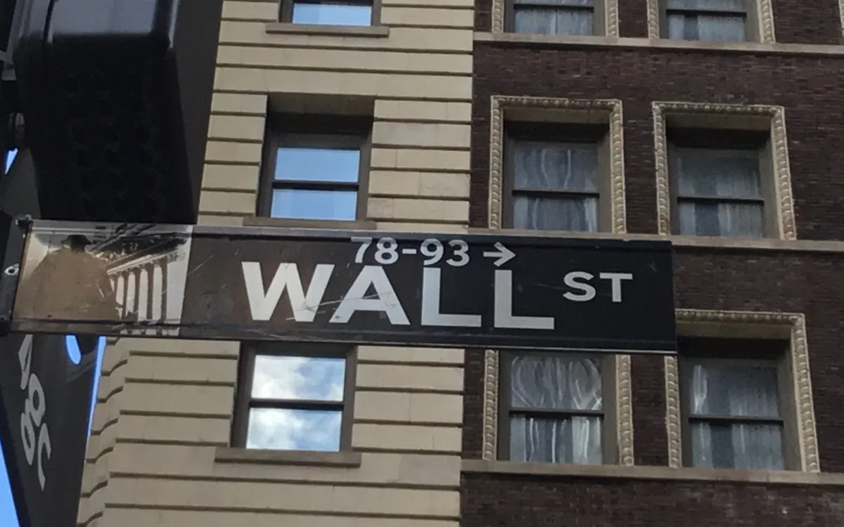 Чорна вулична табличка Wall St на фасаді будинку в Нижньому Мангеттені, Нью-Йорк (ілюстративне фото)