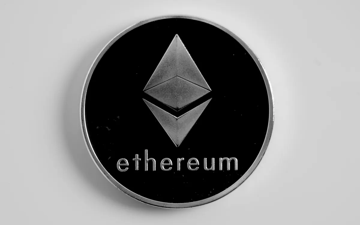 Серебряная физическая монета Ethereum с ромбом ETH на белой поверхности (иллюстративное фото)