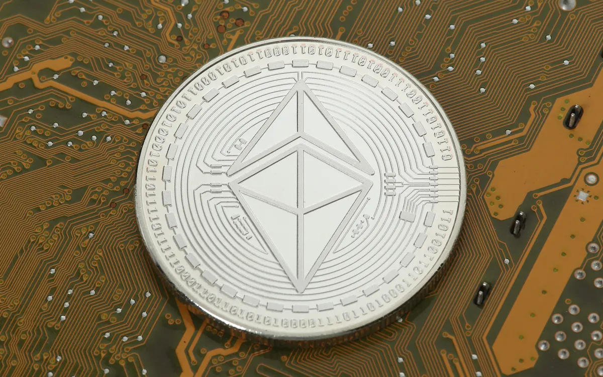 A silver Ethereum souvenir coin lying on a circuit board (illustrative photo)