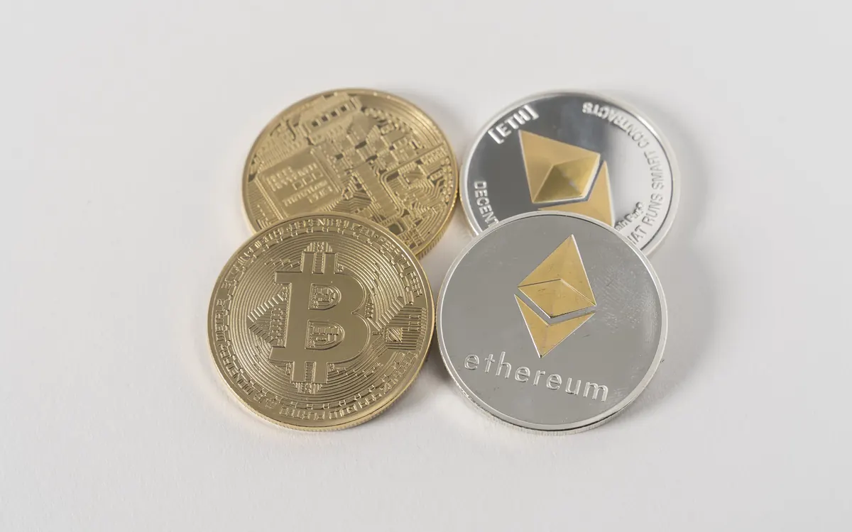 Physical bitcoin and ether souvenir coins on a white surface (illustrative photo)
