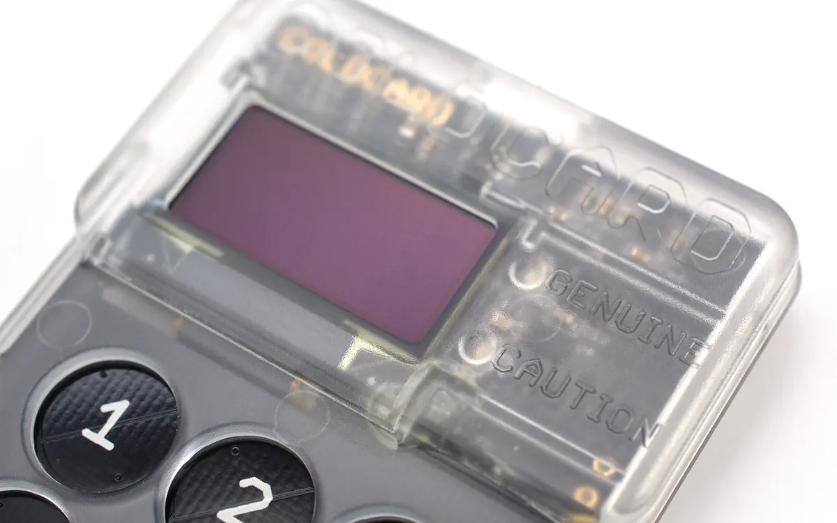 Close-up of a transparent hardware crypto wallet with a small screen and number keys (illustrative photo, not a Keystone device)