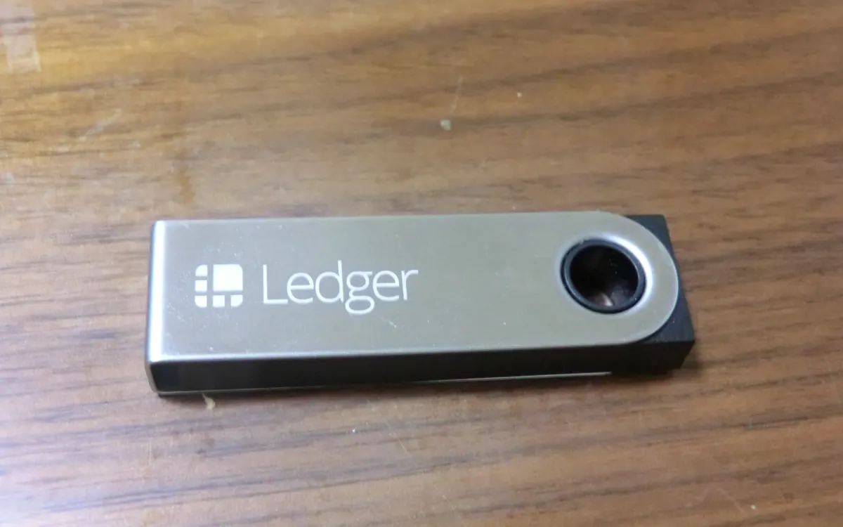 A Ledger Nano S hardware wallet on a wooden surface