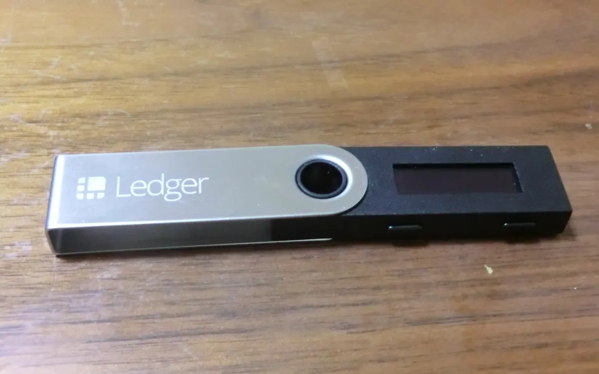 A Ledger Nano S hardware wallet lying on a wooden table (illustrative photo)