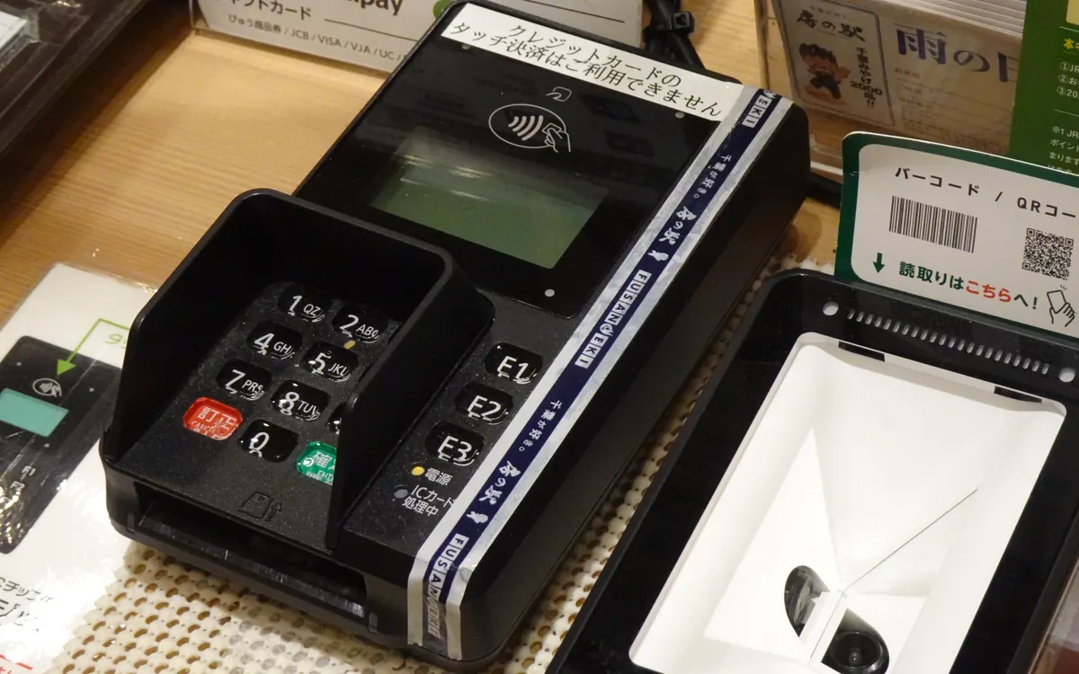 Card payment terminal and QR-code scanner at a shop counter (illustrative photo)