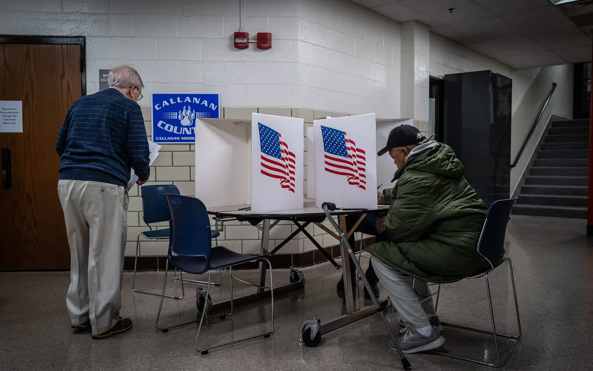 Voters filling in ballots at voting booths with US flags at a polling place in Des Moines on Election Day 2022 (illustrative photo)