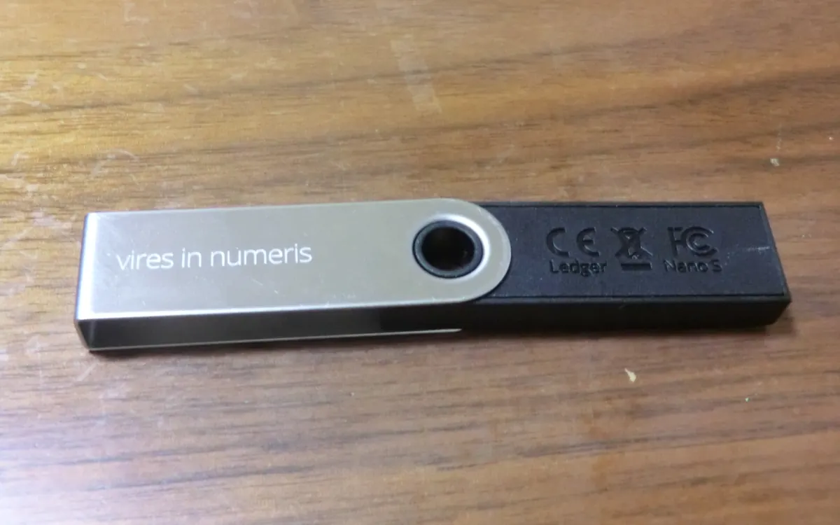 A Ledger Nano S hardware wallet lying on a wooden table (illustrative photo)