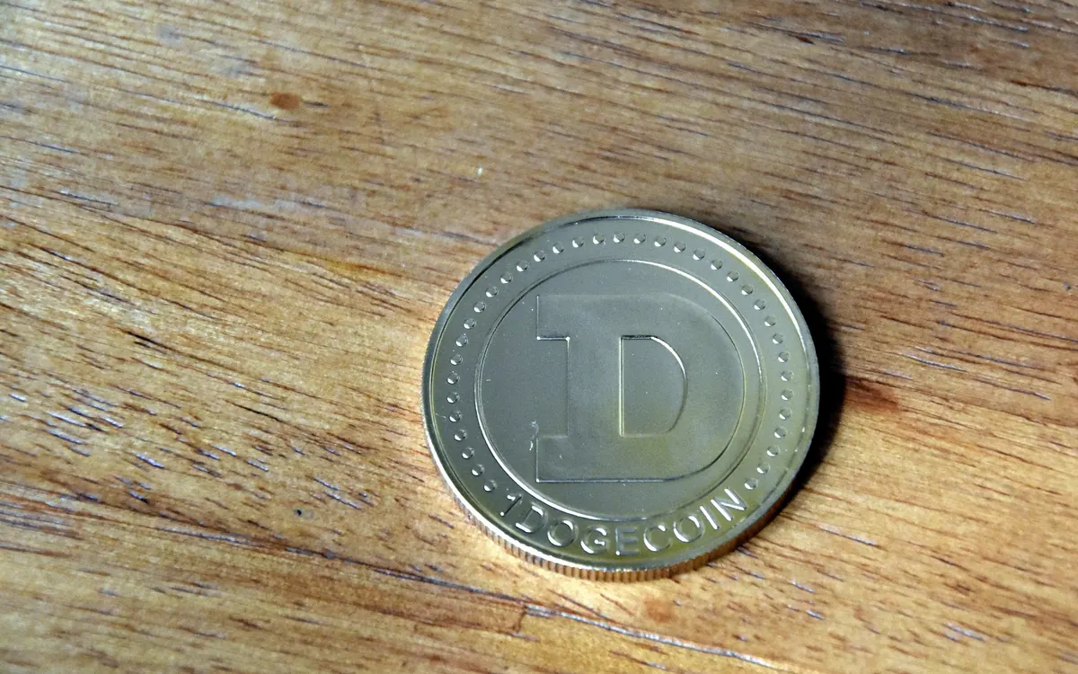 Физическая монета Dogecoin на деревянной поверхности (иллюстративное фото)