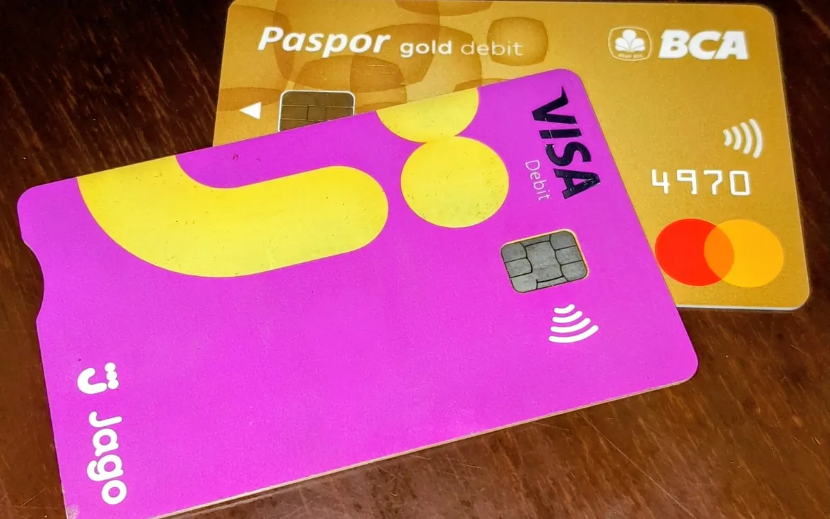 Two overlapping bank cards, one Visa and one Mastercard, on a wooden table (illustrative photo)