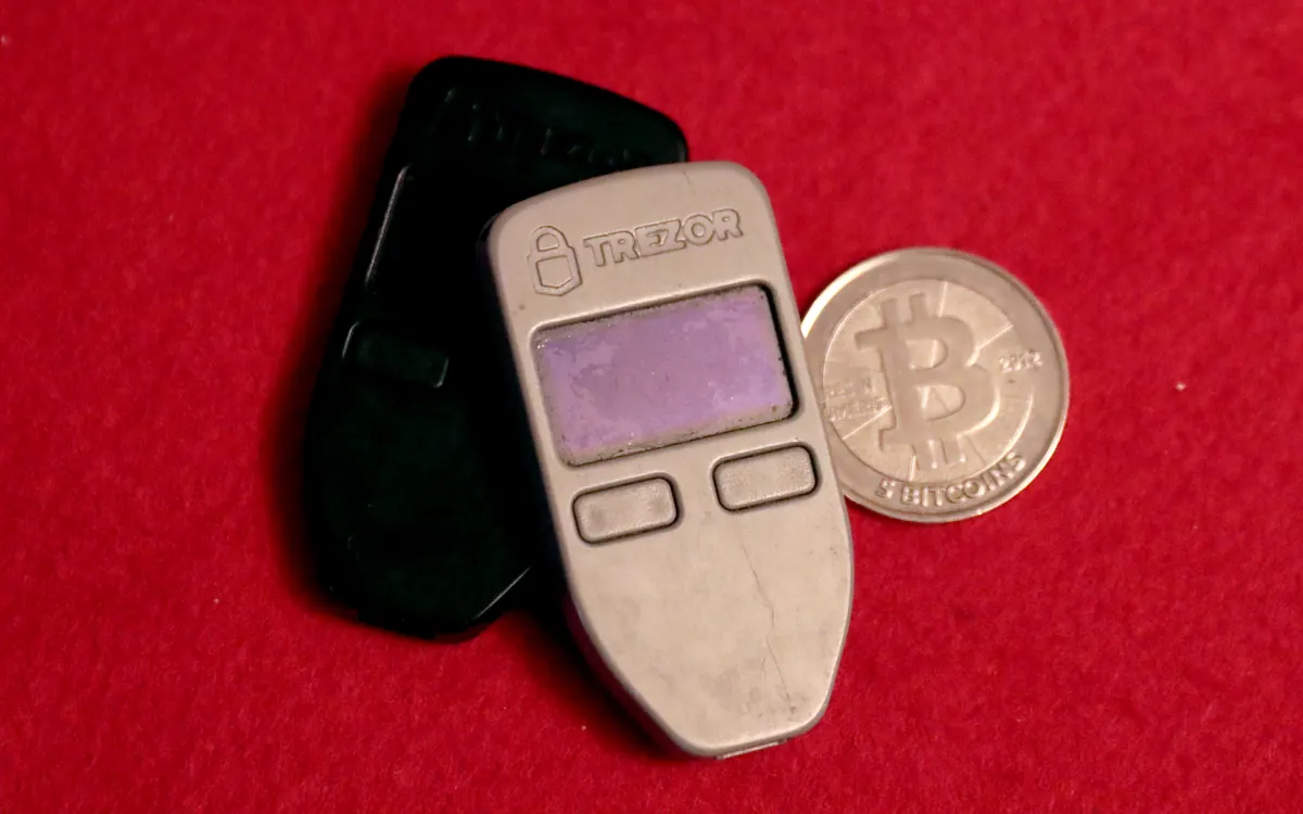 Two Trezor One hardware wallets next to a physical bitcoin coin