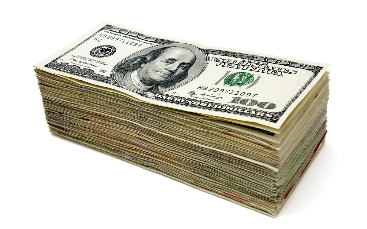 A thick stack of US hundred-dollar bills on a white background (illustrative photo)