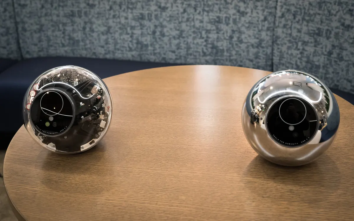 Two of World's iris-scanning Orb devices on display on a wooden table at a 2024 TechCrunch event