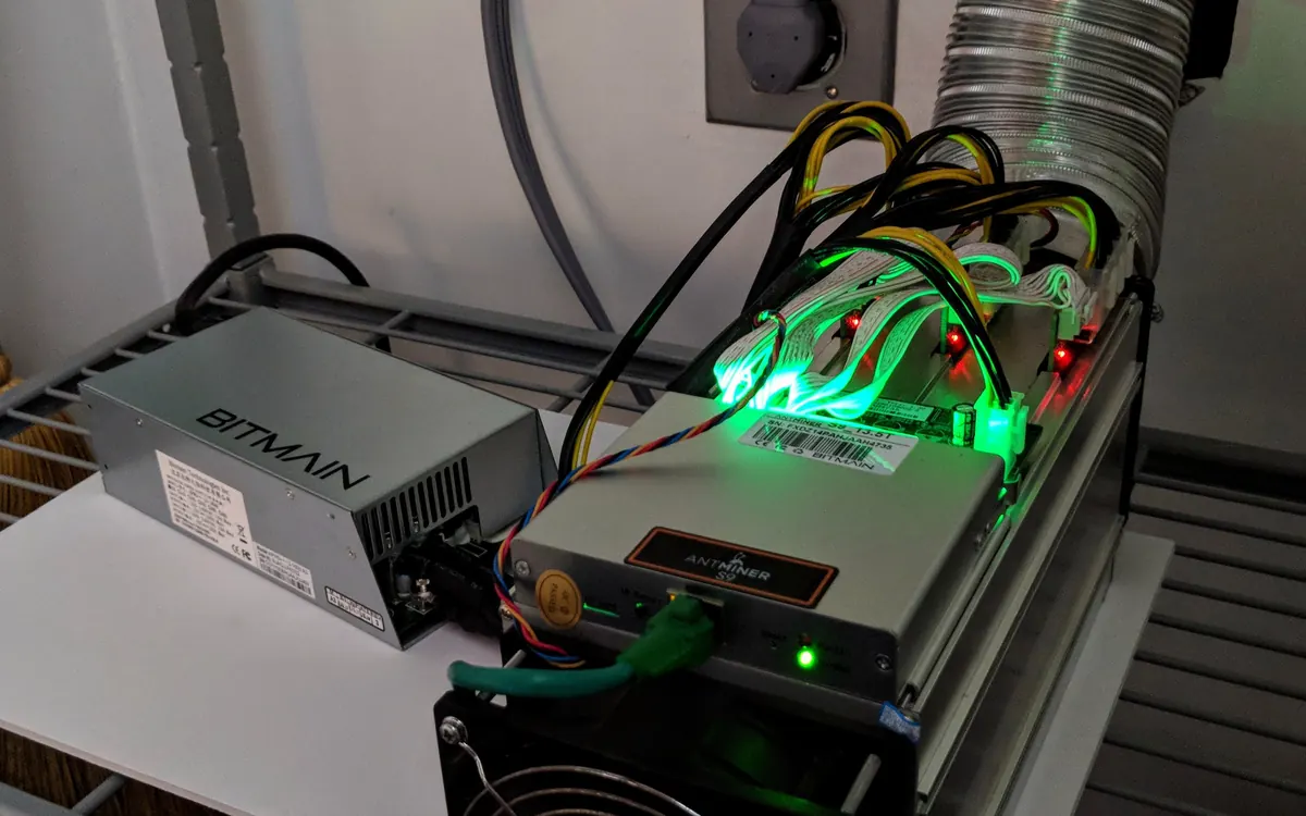 ASIC-майнер Bitmain Antminer із зеленими індикаторами та блоком живлення (ілюстративне фото)