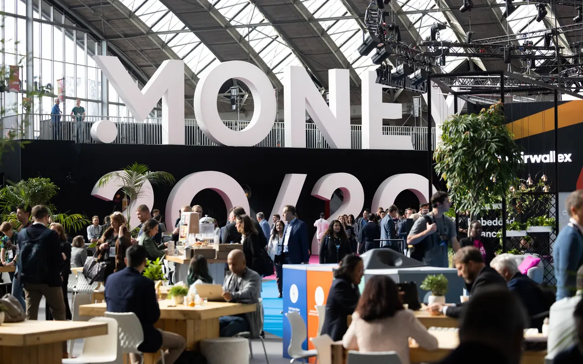 Посетители за столами перед большими буквами Money20/20 на финтех-конференции в Амстердаме (иллюстративное фото)